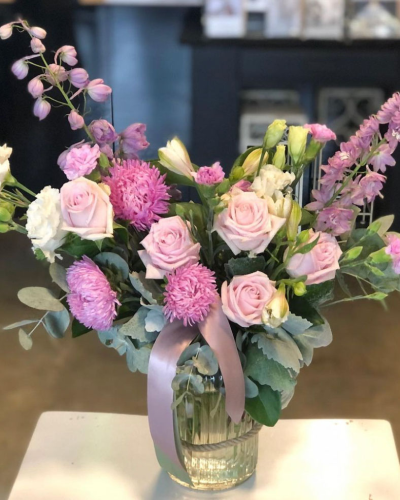 Garden of Eden - A soft and elegant arrangement featuring pale pink roses, delicate chrysanthemums, and white blooms, all arranged in a clear glass vase with a light pink ribbon. This arrangement exudes grace and charm, making it ideal for any thoughtful occasion.